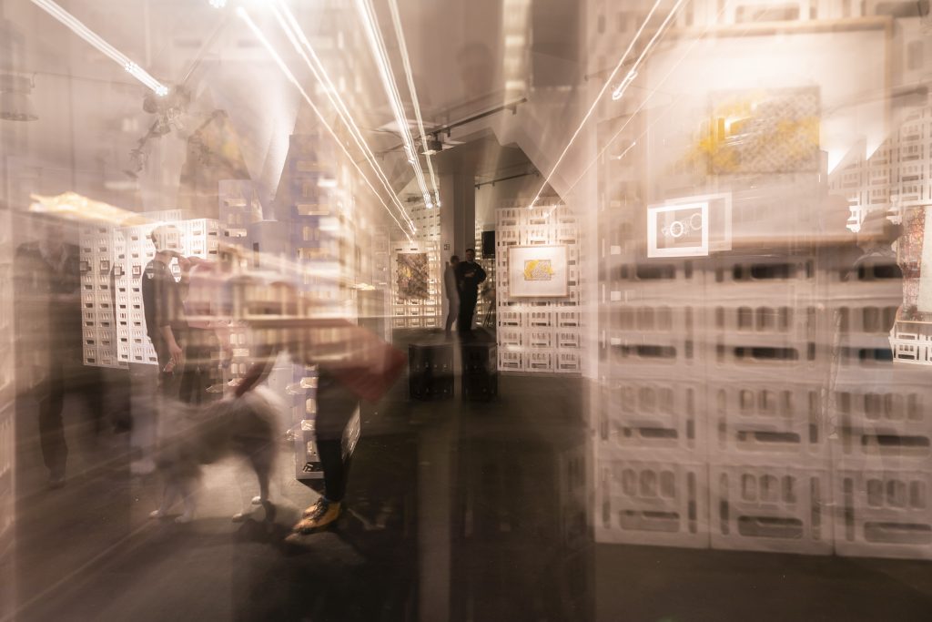 Ausstellungsdesign aus cratedesign® zur Kunstausstellung von Alabaster Becher im KOMPLEX45, mit beleuchteten Wänden an denen Gemälde befestigt sind.